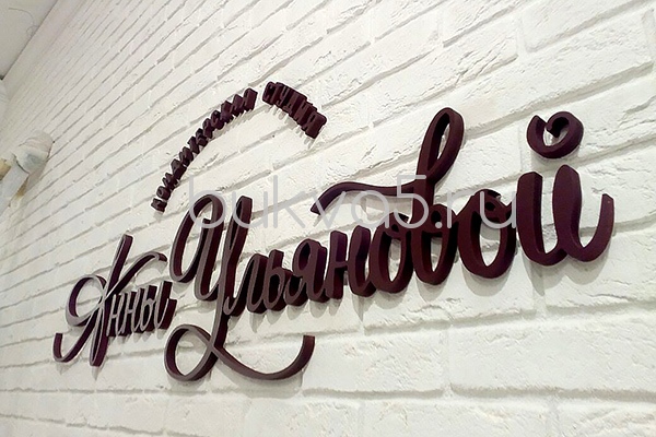 Логотип на стене из вырезанных букв 